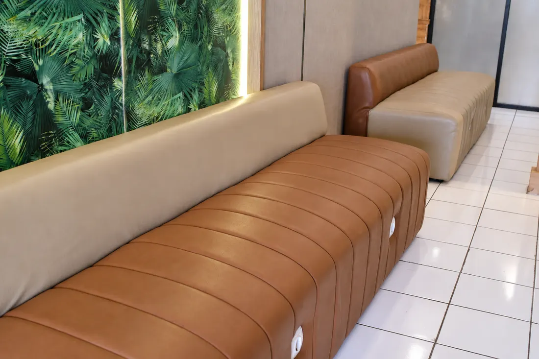 Sofa ruang tunggu Gussy Salon dengan latar dedaunan hijau.